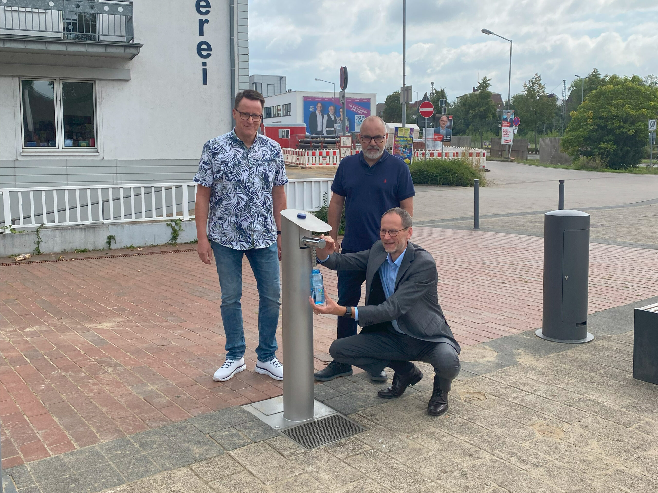Bürgermeister Bernd Poggemöller, Betriebsleiter Matthias Kreft und Thorsten Held, Teamleiter Wasserversorgung, nehmen den Trinkwasserspender am Findeisen-Platz in Betrieb.