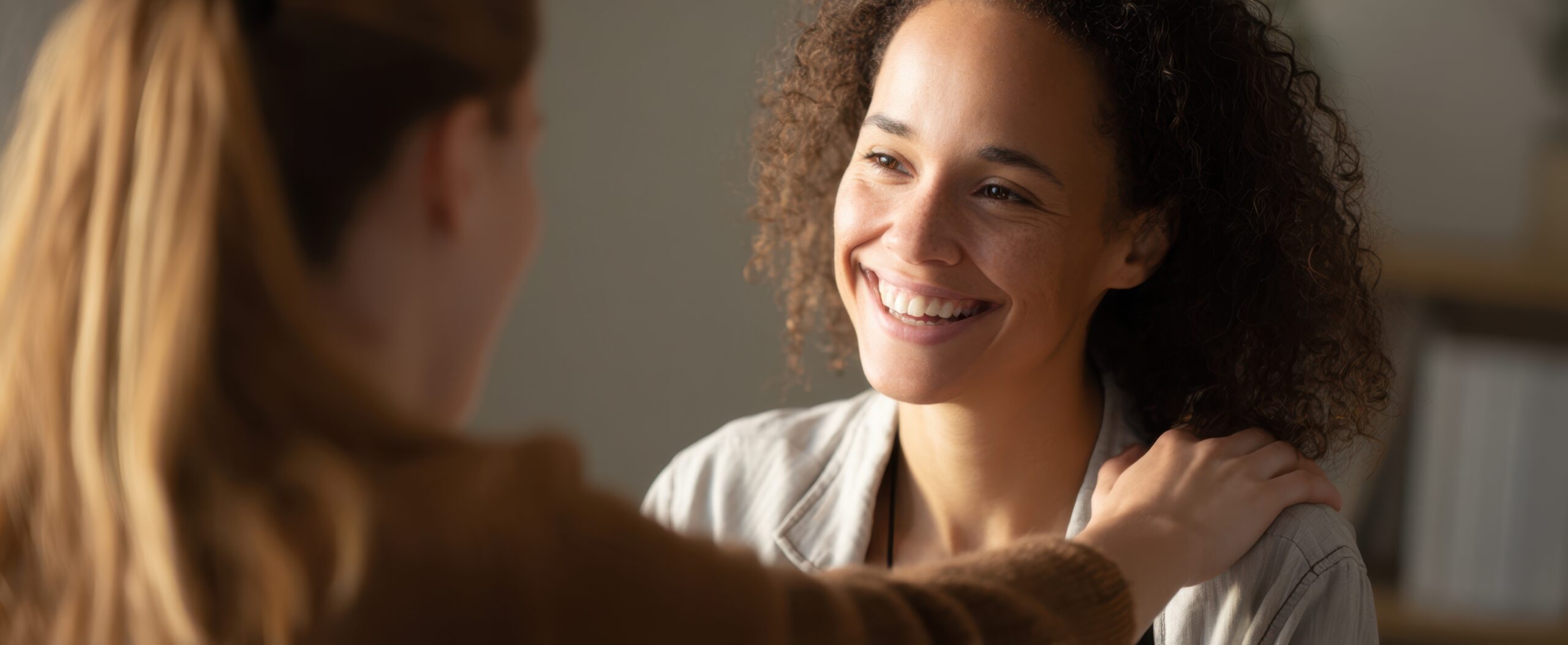 Eine Frau legt die Hand auf die Schulter einer anderen Frau.