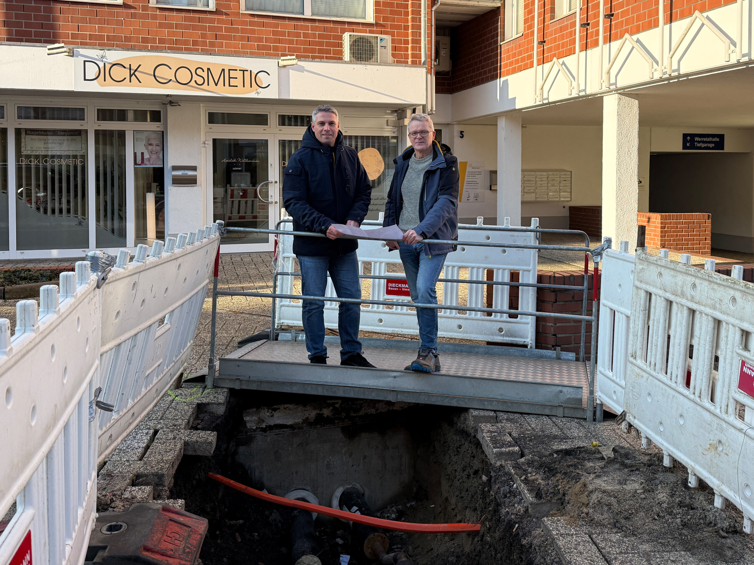 Zwei Mitarbeiter stehen vor einer Nahwärme Baustelle.