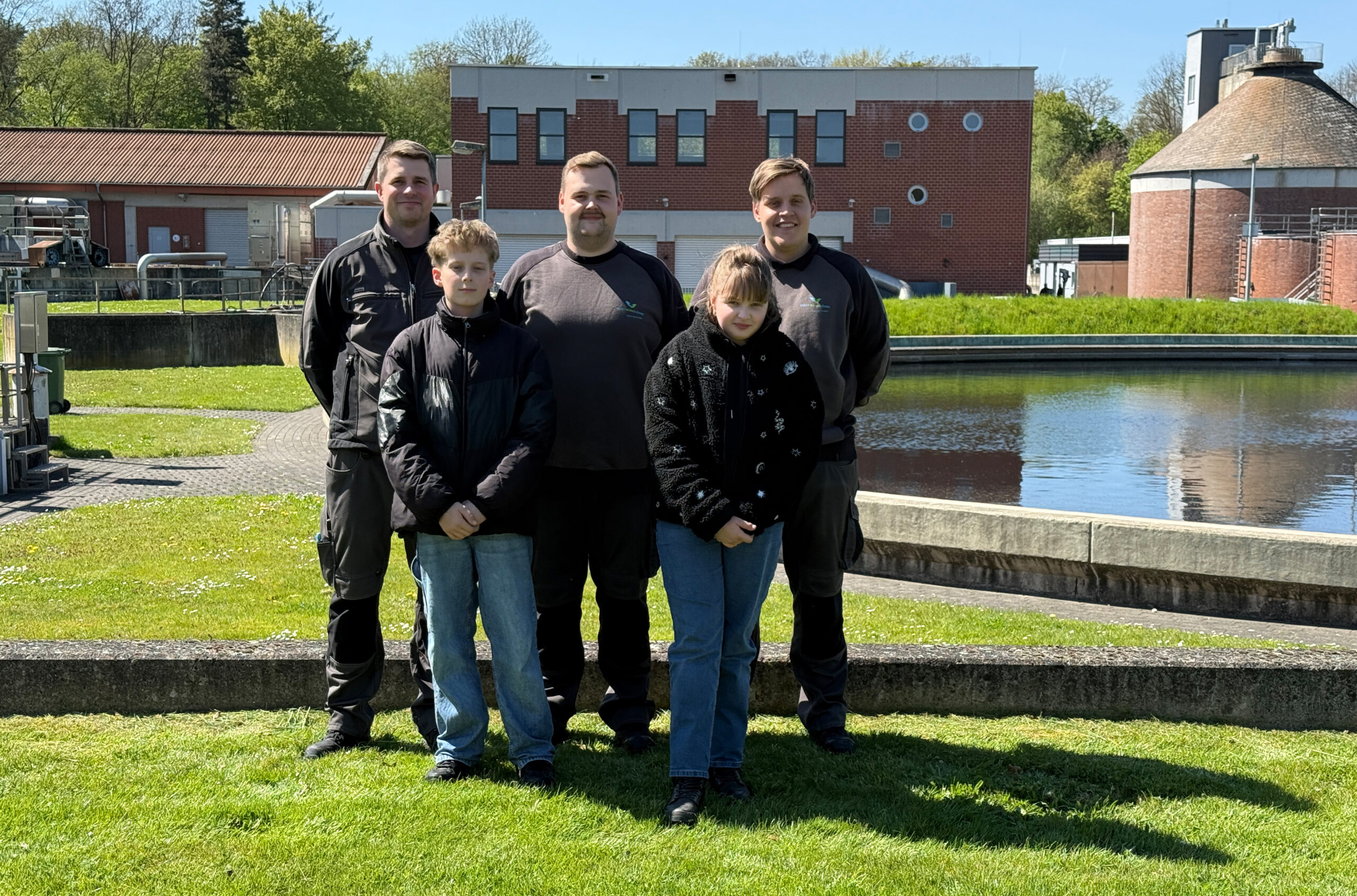 Schüler und Mitarbeiter vor einem Klärbecken