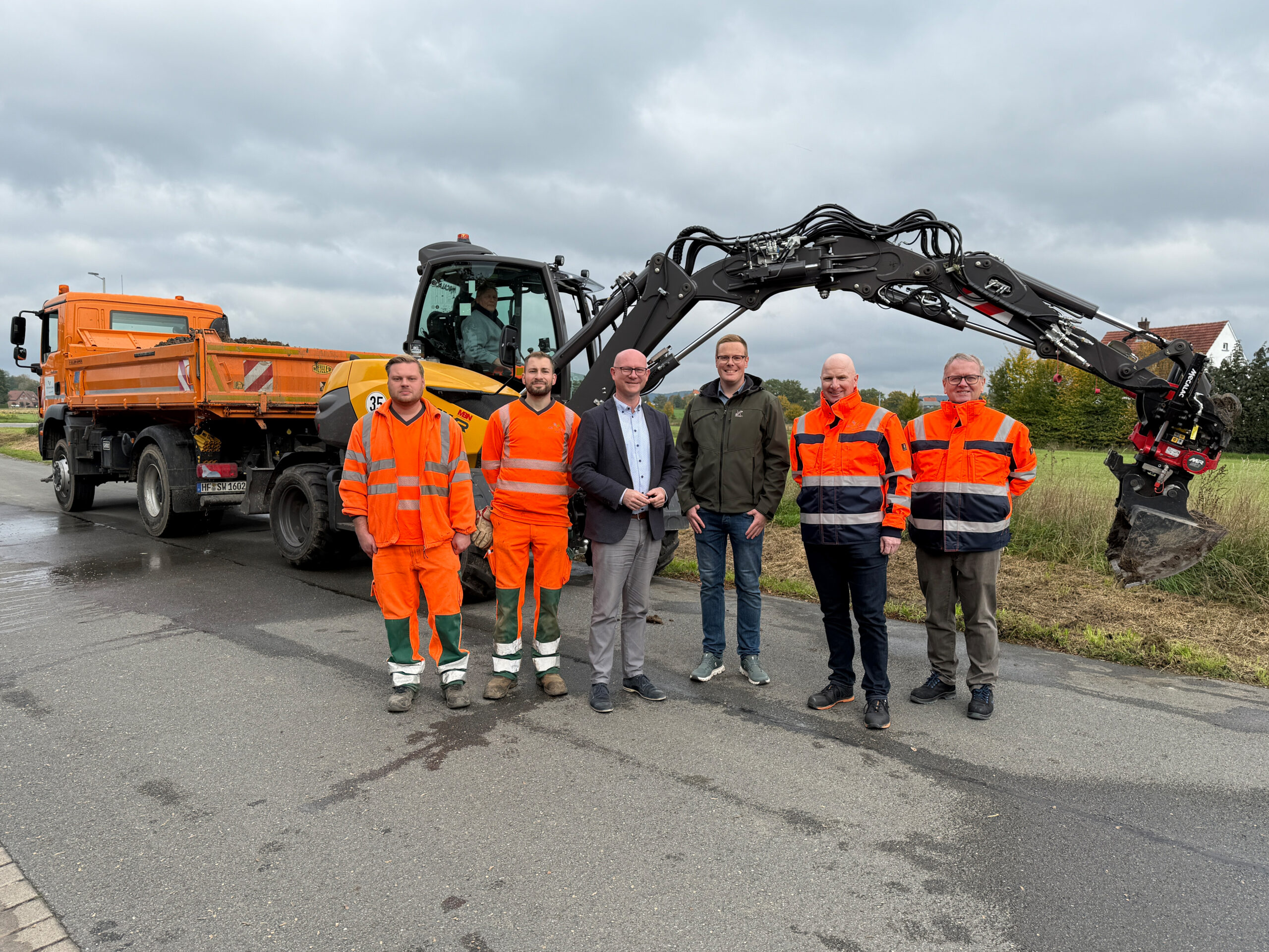 Mitarbeiter stehen vor dem Bagger